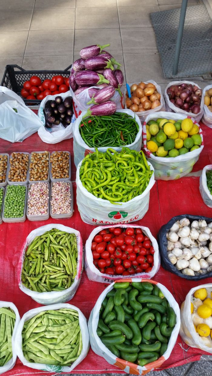 Colorful assortment of fresh vegetables neatly arranged on a market stall outdoors.
